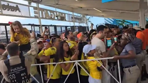 Screenshot of a video showing a young child in a Colombia shirt crying as she is lifted over a security barrier by her family and a police officer.